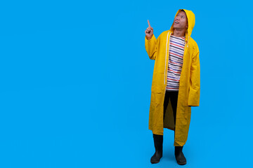 Teenager boy in raincoat pointing away to empty space © Gatot