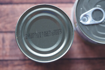 Cans with expiration dates and production codes on wooden surface