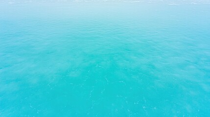 Obraz premium Aerial view of calm, turquoise ocean water with gentle ripples and a clear horizon.