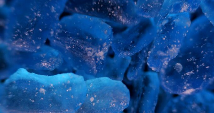 Extreme detailed view of geometric copper sulfate crystals forming in laboratory glassware under bright lighting