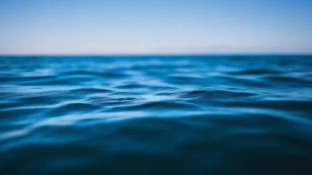 Clear blue ocean water with small gentle waves beneath a bright, cloudless sky.