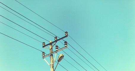 Electric pole with connected wires stretching towards a clean cyan sky backdrop, depicted in a...