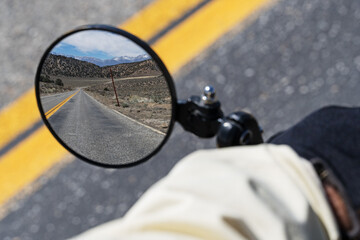 Bicycle Mirror Reflecting An Empty Road Behind An Out Of Focus Hand And Arm