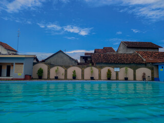Portrait of an outdoor swimming pool surrounded by high walls with a view of the sky