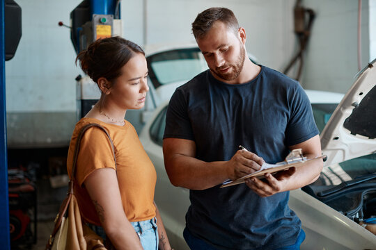 Woman, mechanic and sign document in auto repair shop, invoice and service for car maintenance. Female person, clipboard and customer for vehicle transaction, contract and garage workshop for quote