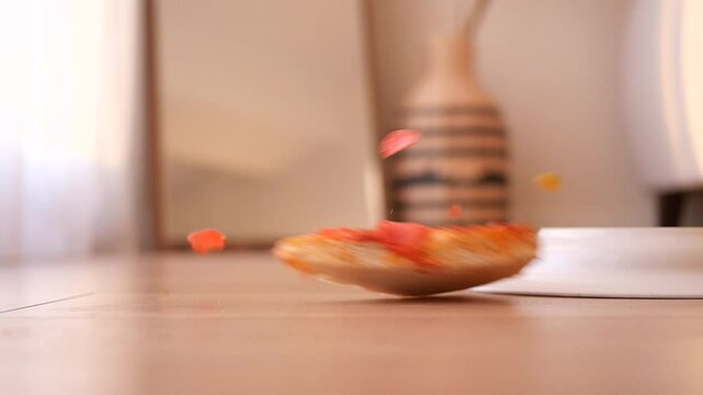 a slice of pizza and plate dropped on a wooden floor 