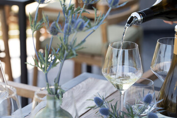 Detail of white wine  being poured into a glass at table