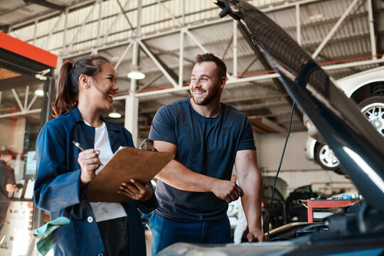 People, car mechanic and workshop with clipboard for inspection on teamwork, collaboration and maintenance. Happy, employee and vehicle repairs or service as engineer with small business and garage