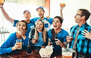 Friends, excited people and watching tv at pub with sport, goal and game at restaurant with celebration. Fan group, smile and happy with drinks, live broadcast and match together at bar with alcohol