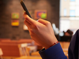 カフェでスマホを弄る男性の片手とスマホの様子