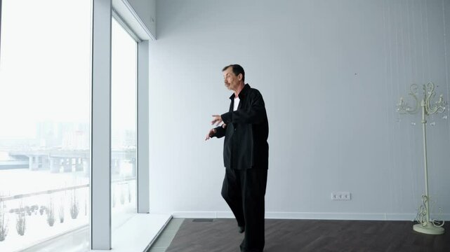 Senior man performing tai chi chuan exercises in studio