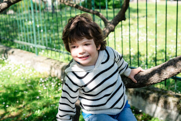 Happy child playing on a tree branch outdoors