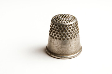 Close-up of a vintage thimble, showcasing its intricate perforated design. Ideal for sewing enthusiasts and collectors, this image captures the charm of traditional crafting tools.