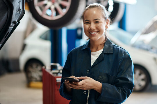 Portrait, mechanic and woman with smartphone in auto repair shop, smile and internet for online schedule. Face, inspection and person with cellphone in garage and vehicle maintenance with opportunity