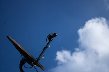 View looking up at a rusty satellite dish silhouetted against a blue sky with clouds. Represents...