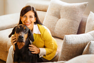 Smiling businesswoman hugging her doberman pinscher at home