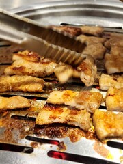 Grilled Pork Belly on Hot Pan with Tongs Close-Up