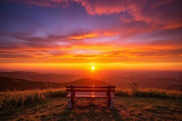 Fototapeta premium Scenic vista of a tranquil sunset over a mountain range with an empty wooden bench.