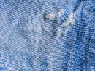 Close-up of distressed vintage denim. Details of old torn jeans. Torn, worn blue jeans fabric...