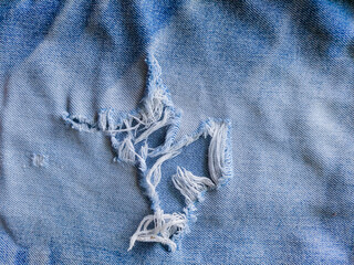 Close-up of distressed vintage denim. Details of old torn jeans. Torn, worn blue jeans fabric...