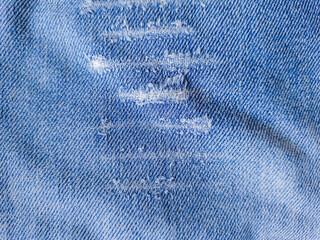 Close-up of distressed vintage denim. Details of old torn jeans. Torn, worn blue jeans fabric...