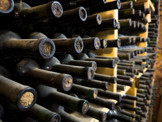 Old bottles of wine stacked in rows in the cellars of a winery