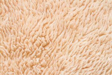 The texture of faux fur is peach colored. Faux fur close-up.