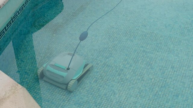 robotic pool cleaner scrubs tiled floor underwater in clear blue pool