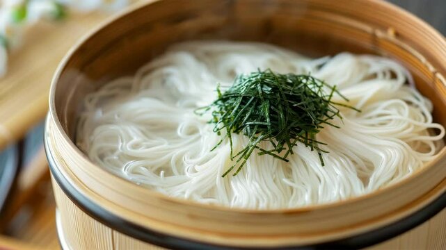 蒸籠に盛り付けられた温かいそうめんと刻み海苔