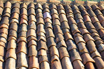 Old worn tiles. Building material background. Red tiles that require maintenance. Roofing, waterproofing. Surface. Top view, above. 