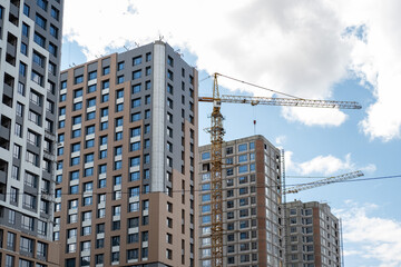 Fototapeta premium Construction crane on Housing. Construction of the Multi Storey Residential Building. Construction of a skyscraper. Tower Crane on formworks on construction site. Buildings under construct.
