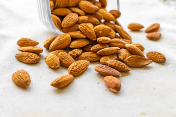 Roasted organic almonds in a glass bowl standing on the table, top and side view