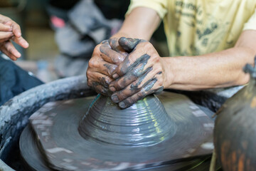Close-up of hands shaping clay on a spinning pottery wheel.