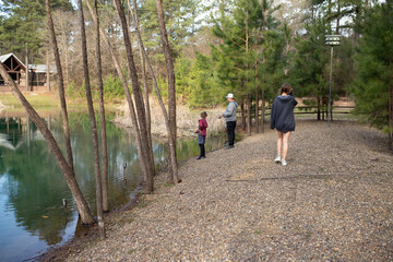 family fishing on a rock shore at pond by cabin