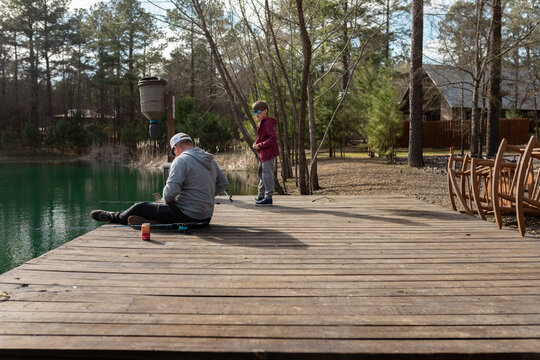father and son with fishing rods on wooden dock