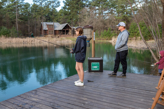 Family fishing from dock with catch and release sign by lake cabin