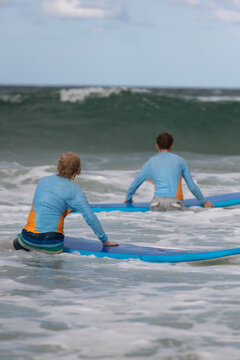 Two beginner boys walking out to wave - learn to surf