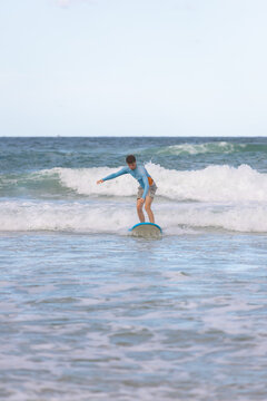 Teen balances on blue foam board during beginner surf ride