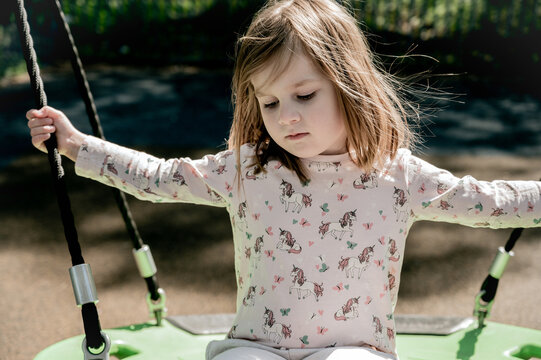 Sad toddler girl on swing, playground. Education, activity outdoor