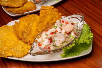 Enjoy delicious ceviche with crispy fried plantains, beautifully presented on a wooden table