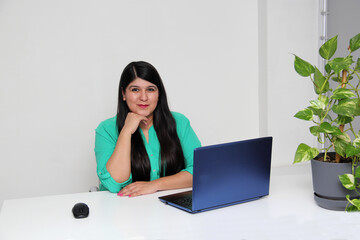 30-year-old Latina woman works in an office with a laptop. As a successful and entrepreneurial woman, she enjoys doing business