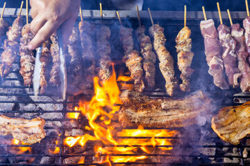 A grill filled with skewers of meat cooking over open flames.