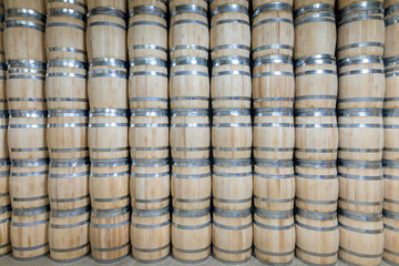 Rows of wooden barrels are neatly stacked in a storage area
