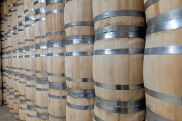 Rows of wooden barrels are neatly stacked in a storage area