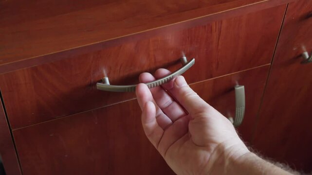 A hand opens a drawer containing jewelry and money, including pearls, rings, and banknotes, symbolizing access to wealth and valuables