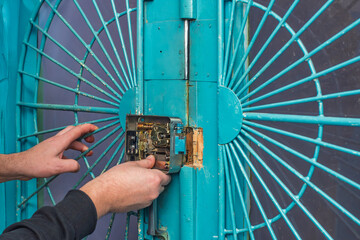 Handyman installing lock in metal door, closeup photo. Adjusting surface lock on door, installation...