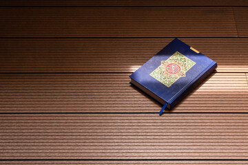 Holy Al Quran with written arabic calligraphy with natural daylight on wooden background