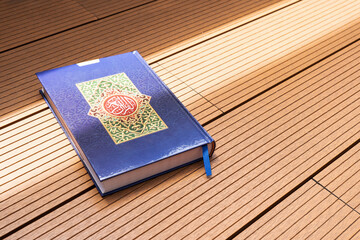 Holy Al Quran with written arabic calligraphy with natural daylight on wooden background