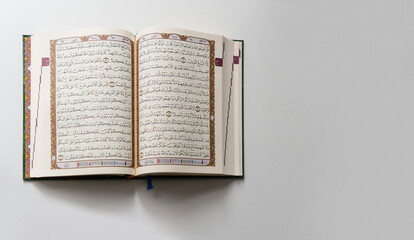 Obraz premium Bandung, Indonesia - 02.11.2025: Photo of opened Holy Quran with Arabic calligraphy on white background