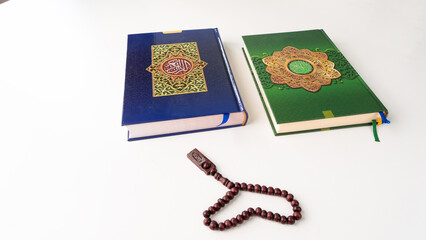 Two of Holy Quran with Arabic calligraphy with wooden beads or tasbih on white background